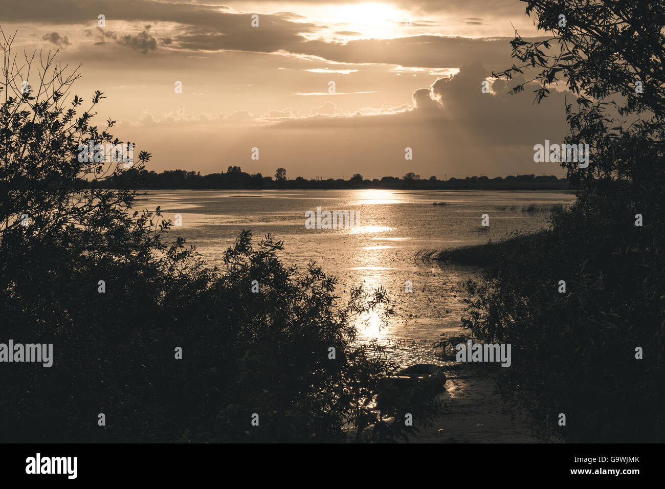 Coucher du soleil d'été sur le lac et sur la rive bateau solitaire Banque D'Images
