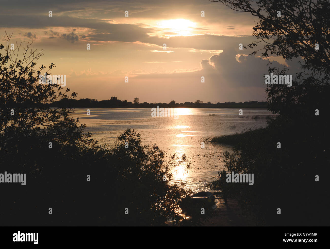 Coucher du soleil d'été sur le lac et sur la rive bateau solitaire Banque D'Images