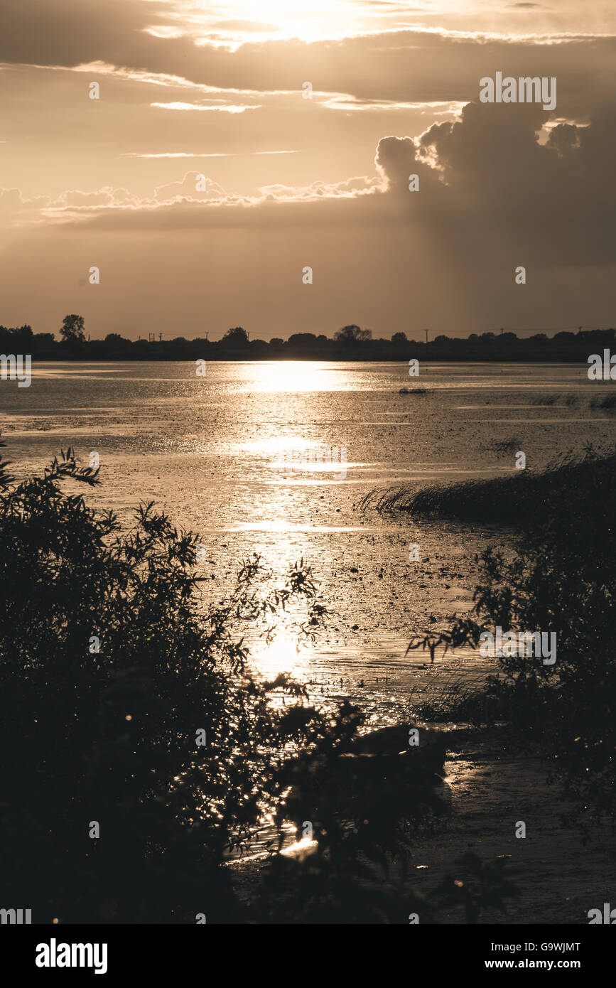 Coucher du soleil d'été sur le lac et sur la rive bateau solitaire Banque D'Images