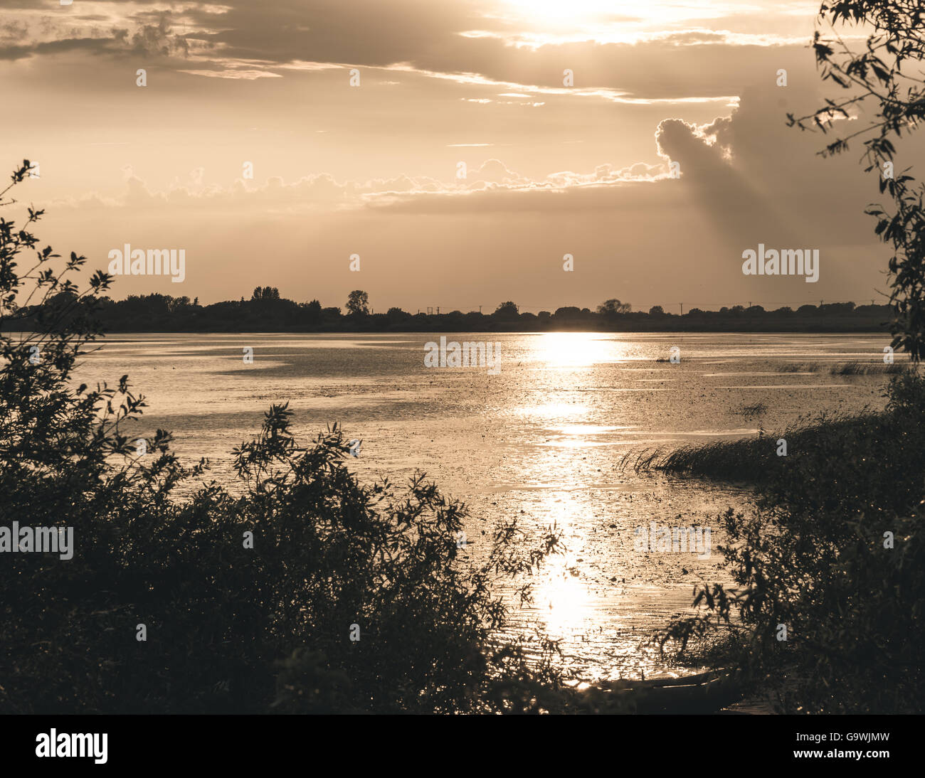 Coucher du soleil d'été sur le lac et sur la rive bateau solitaire Banque D'Images