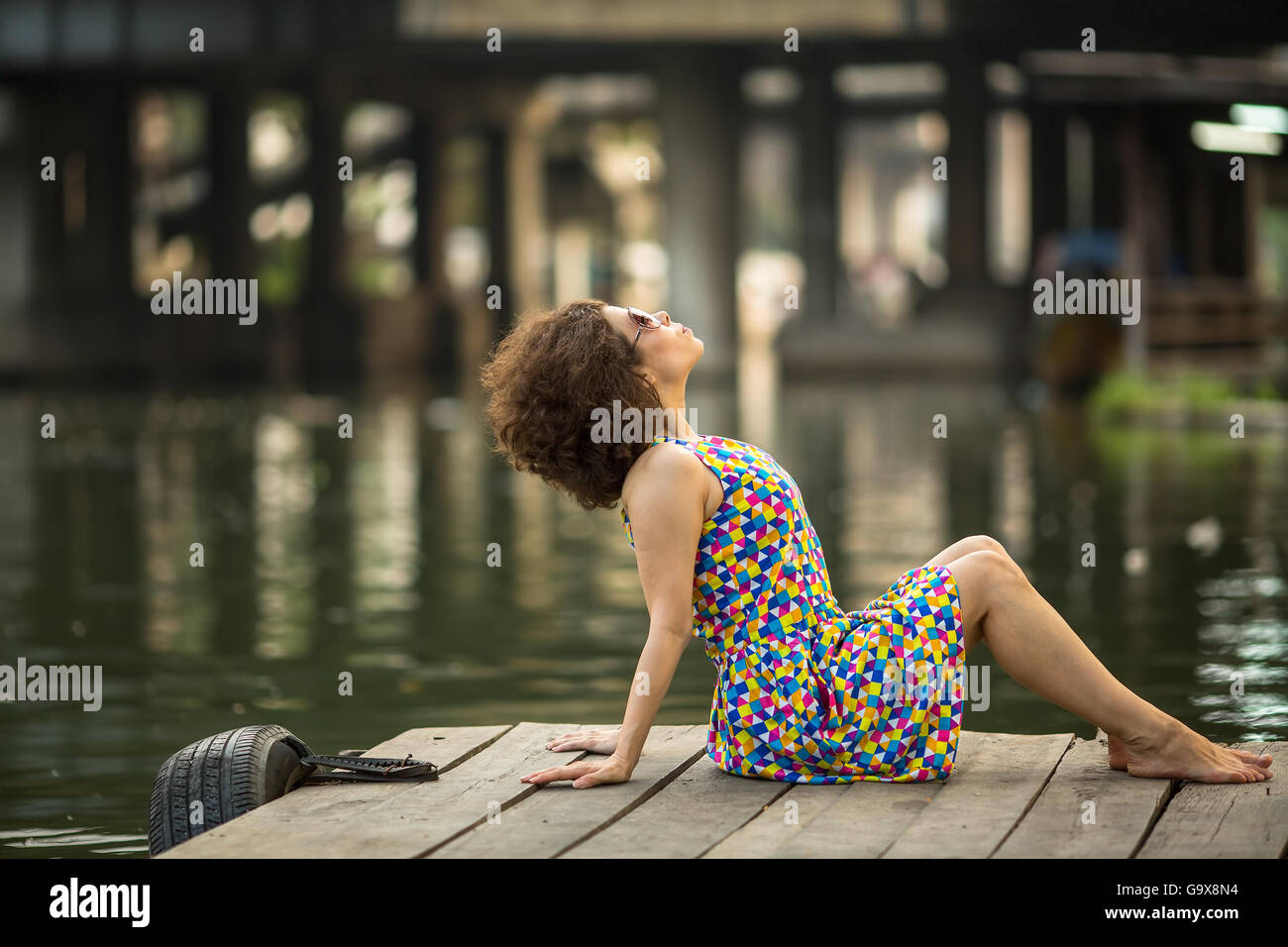 Jeune fille asiatique spectaculaire est assis sur un quai de la rivière. Banque D'Images