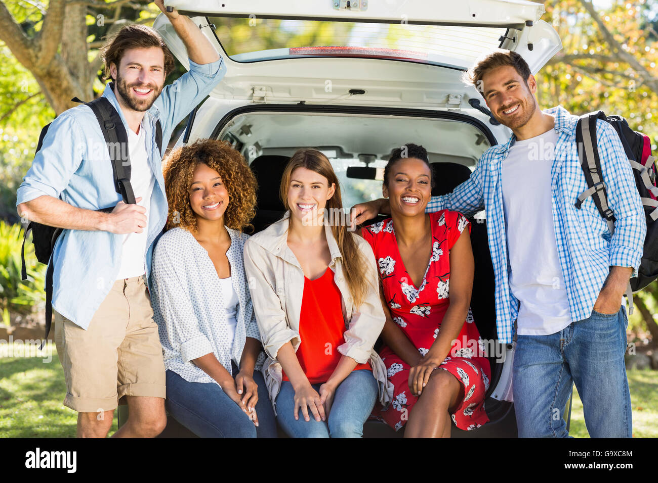 Groupe d'amis sur le voyage assis dans coffre de voiture Banque D'Images