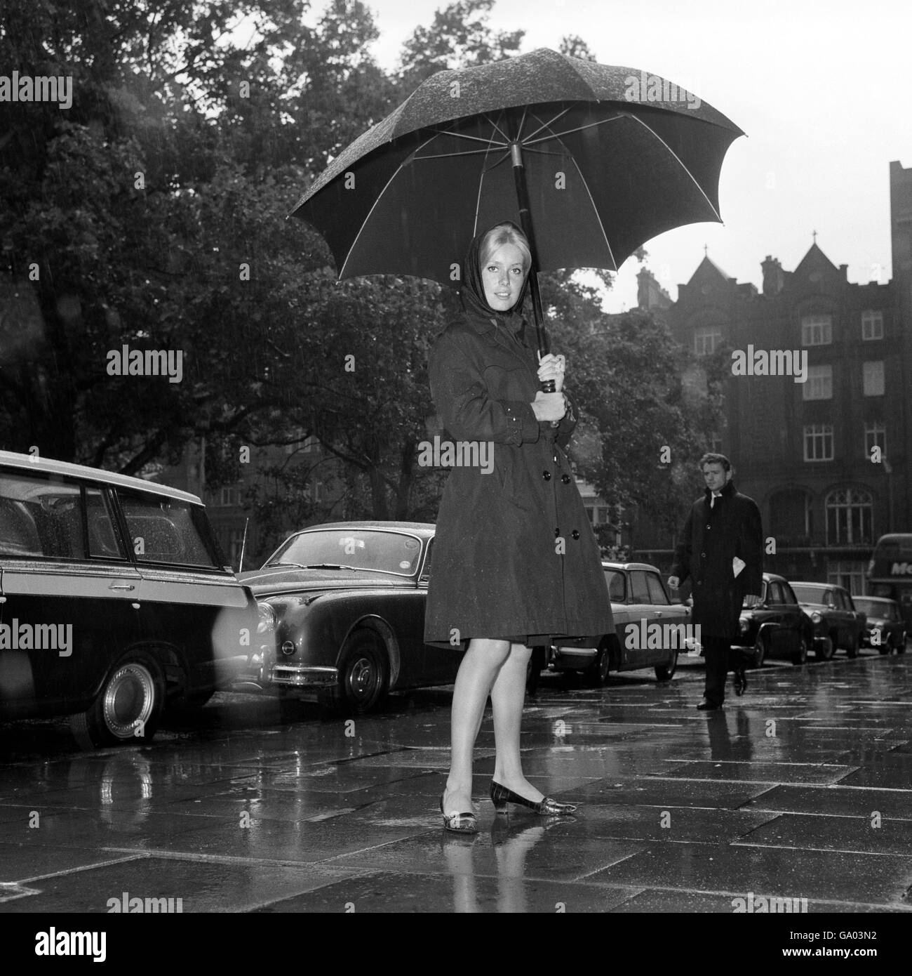 Catherine Deneuve, actrice française utilisant un parapluie alors qu'elle quittait son hôtel de Londres pour aller travailler sur la répulsion du film. Banque D'Images