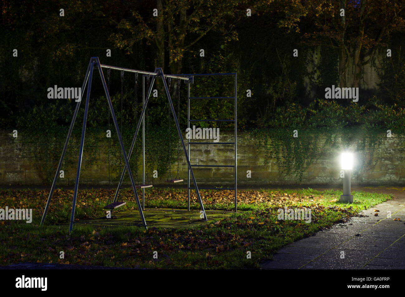 Une aire de jeux avec balançoires métal vide la nuit avec brouillard et atmosphère creepy Banque D'Images