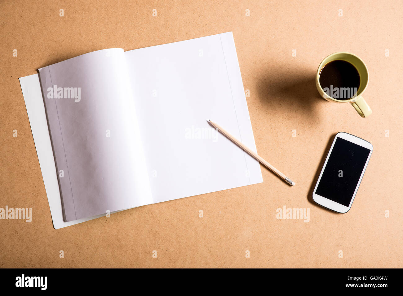 Un smartphone et un livre d'exercice sur un bureau en bois. Banque D'Images