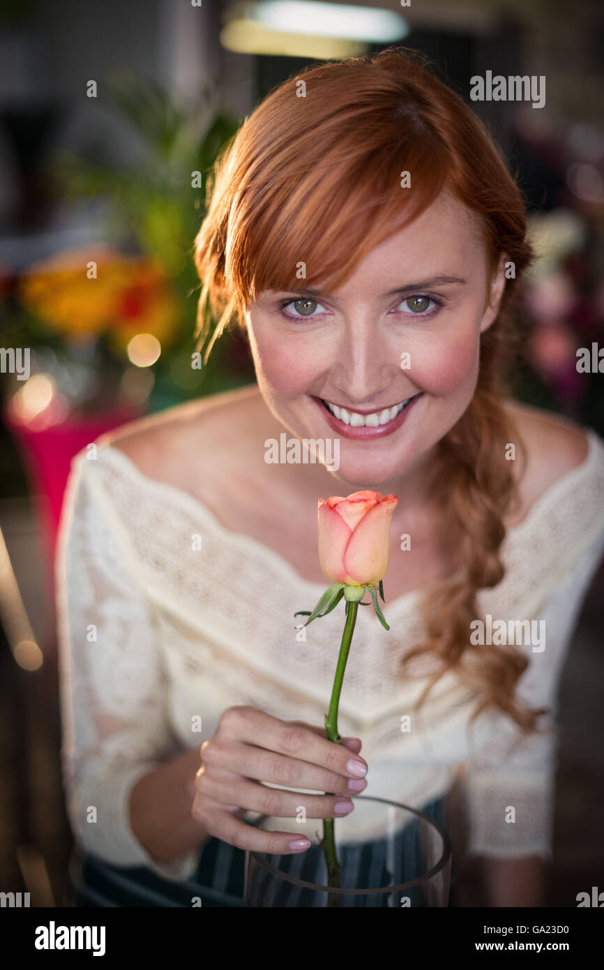 Portrait of female florist sentir une fleur rose Banque D'Images