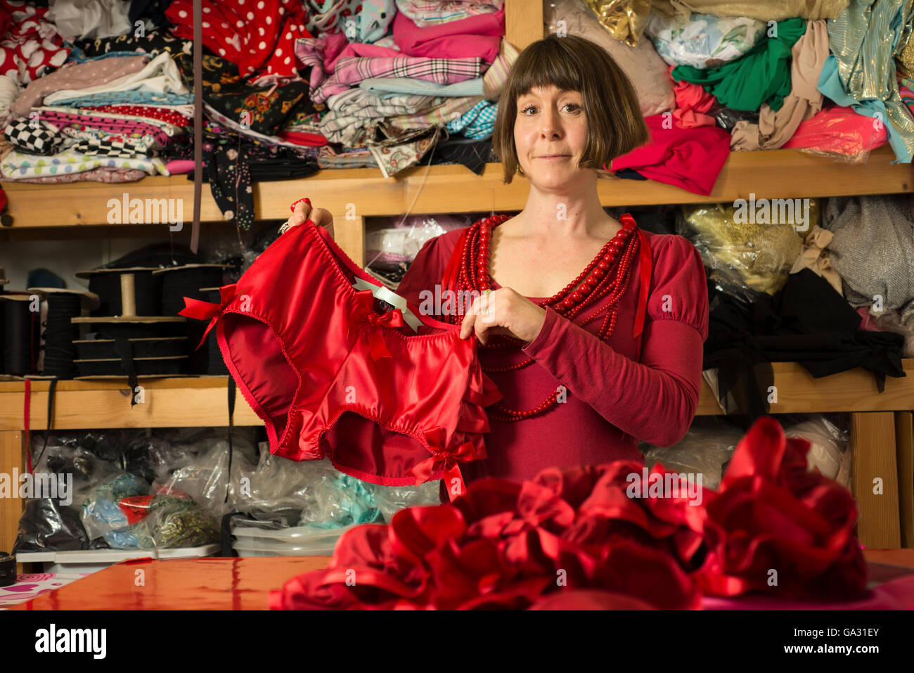 Une femme en robe rouge sur mesure affichage culottes rouges cousues récemment Banque D'Images