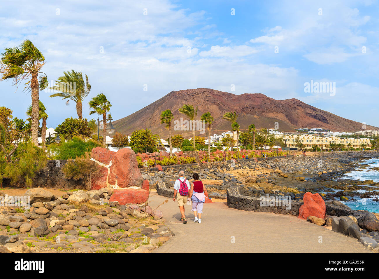 Couple de touristes marcher sur les côtes de l'océan le long de la promenade de Playa Blanca, Lanzarote, îles Canaries, Espagne Banque D'Images