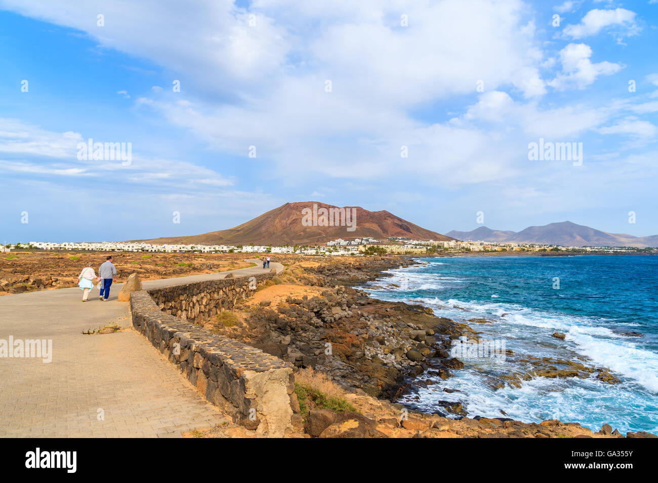 Quelques touristes sur les côtes de l'océan le long de la promenade de Playa Blanca, Lanzarote, îles Canaries, Espagne Banque D'Images