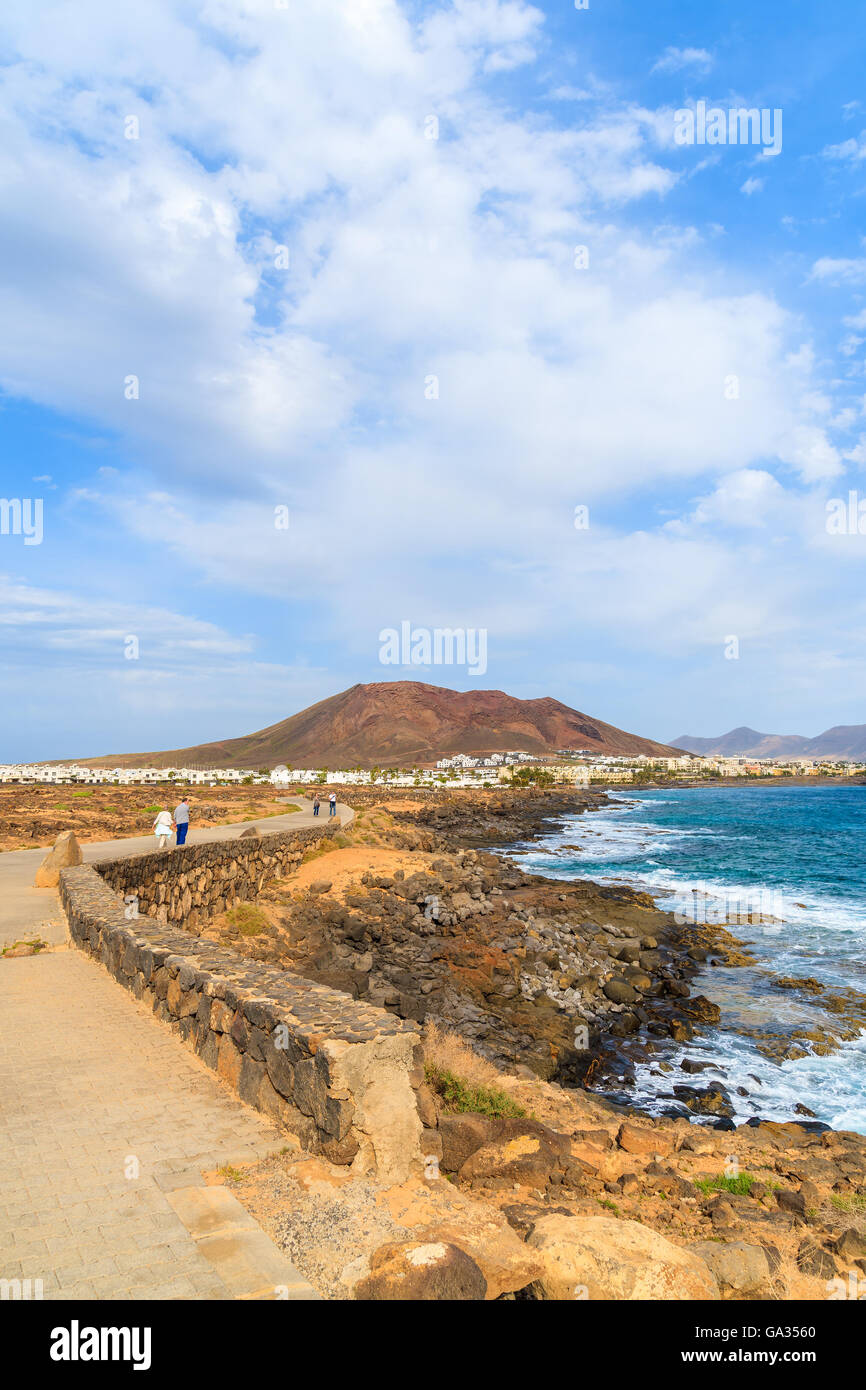 Quelques touristes sur les côtes de l'océan le long de la promenade de Playa Blanca, Lanzarote, îles Canaries, Espagne Banque D'Images
