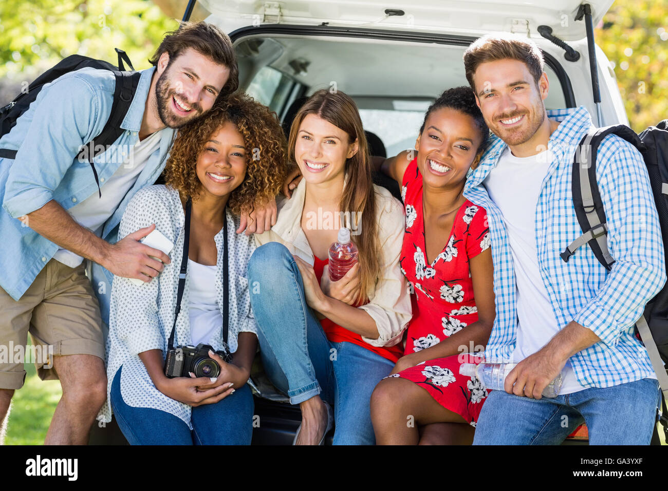Groupe d'amis sur le voyage assis dans coffre de voiture Banque D'Images