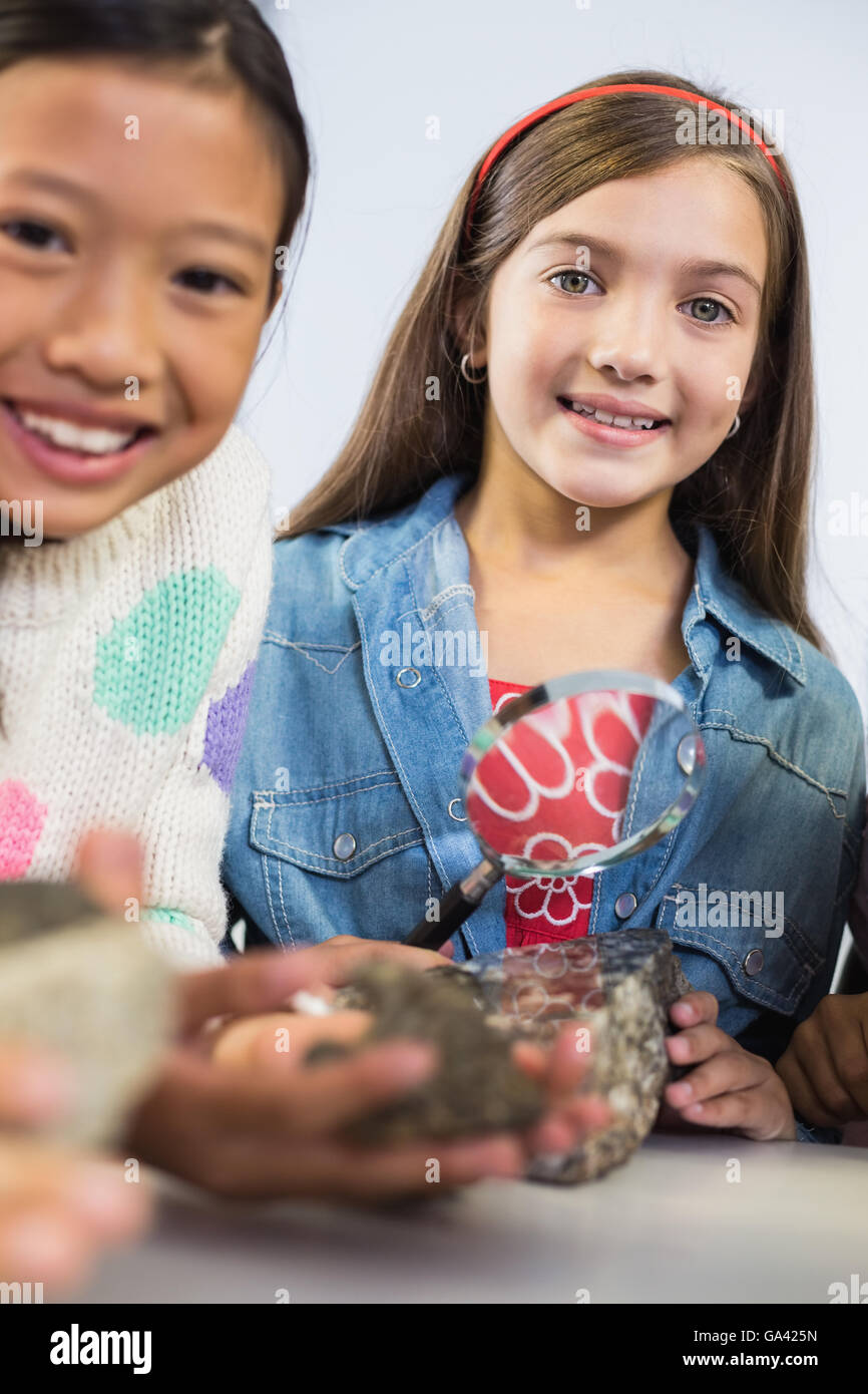 Portrait de kids holding magnifying glass in classroom Banque D'Images