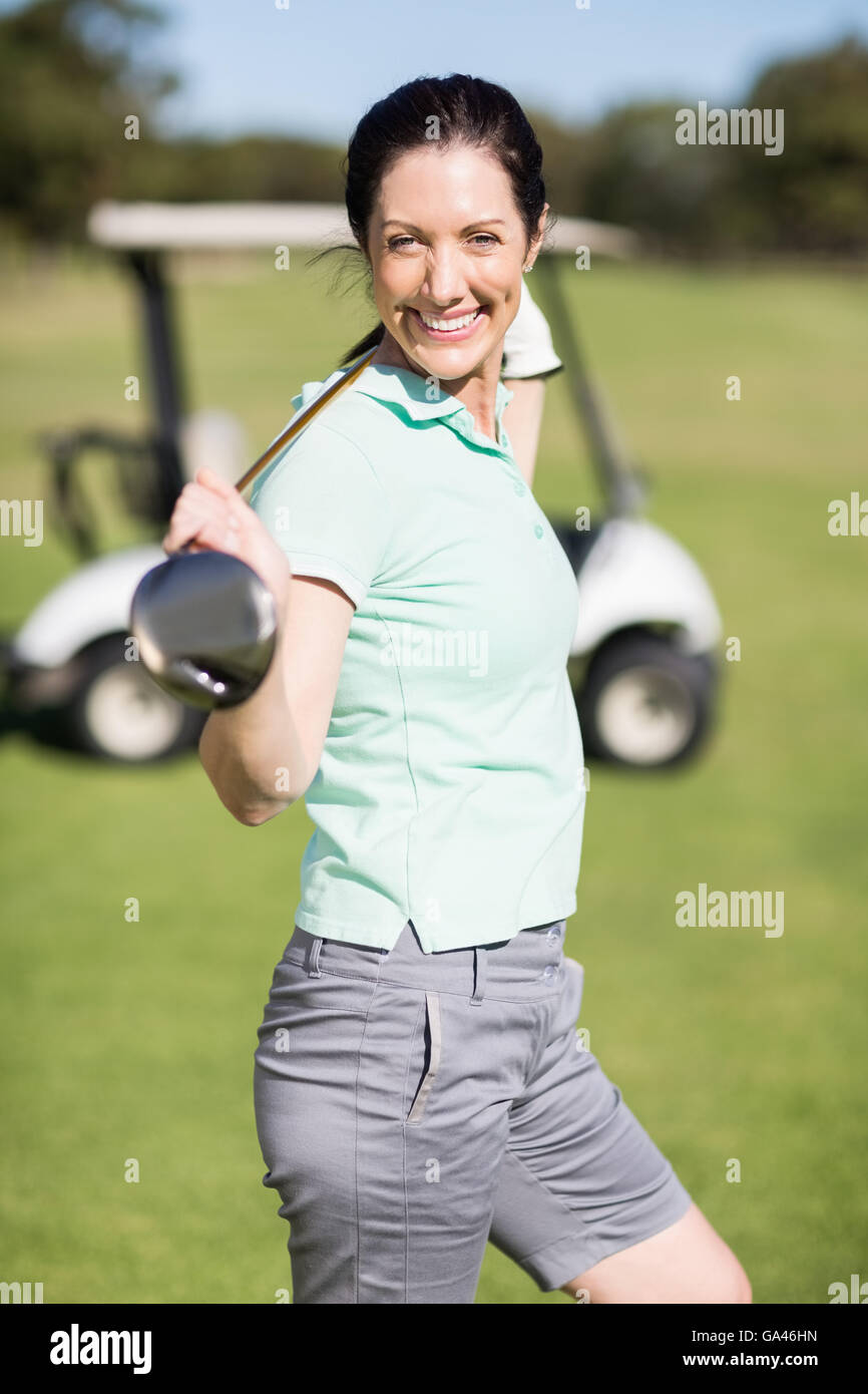 Vue latérale du cheerful woman carrying golf club Banque D'Images
