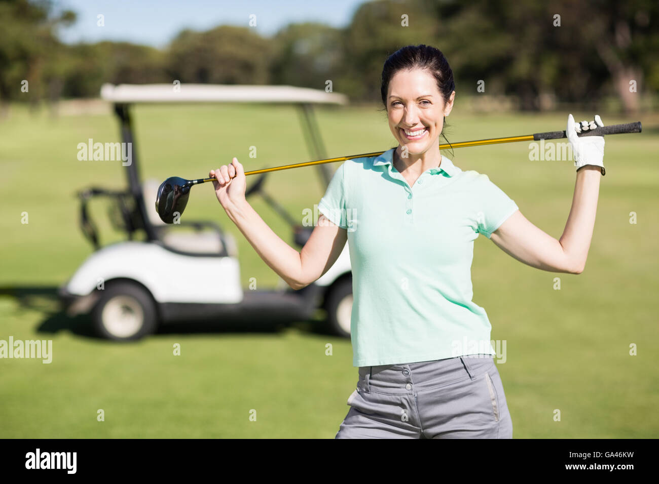 Portrait of smiling woman carrying golf club Banque D'Images