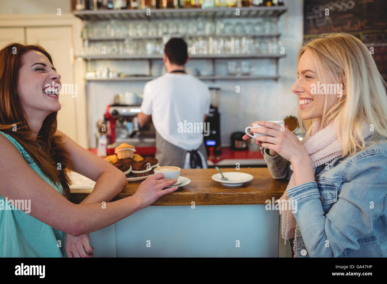 Les clients gai parler à compteur dans coffee shop Banque D'Images
