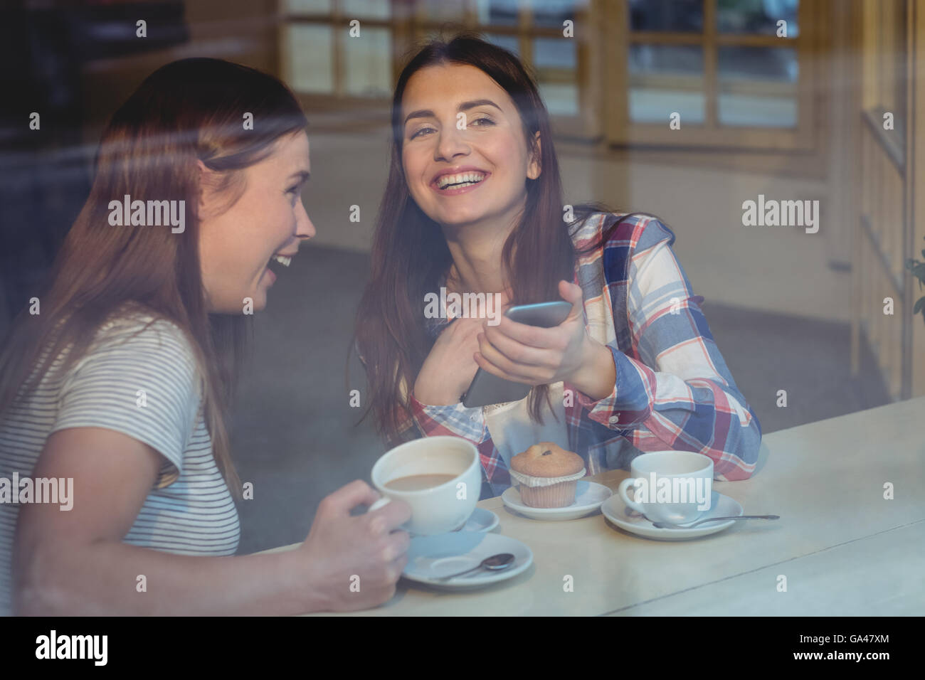 Cheerful women with cellphone at coffee shop Banque D'Images