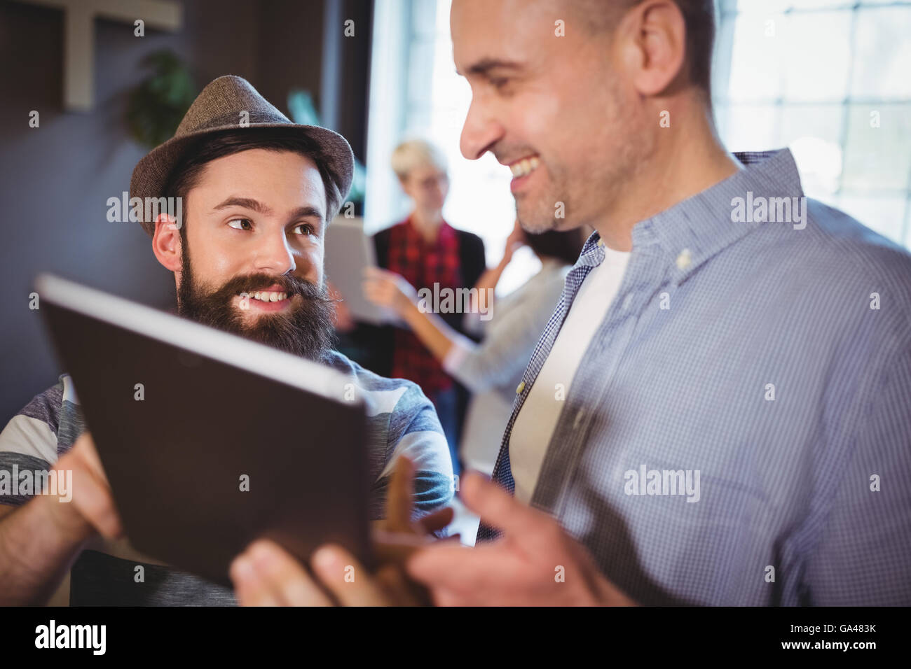 Heureux collègues hommes discutant sur tablette numérique Banque D'Images