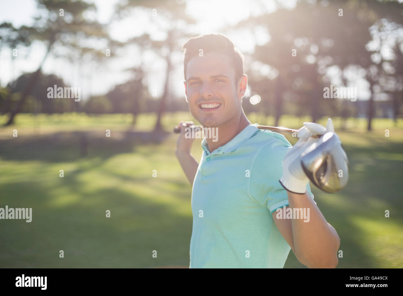 Portrait of happy young man carrying golf club Banque D'Images