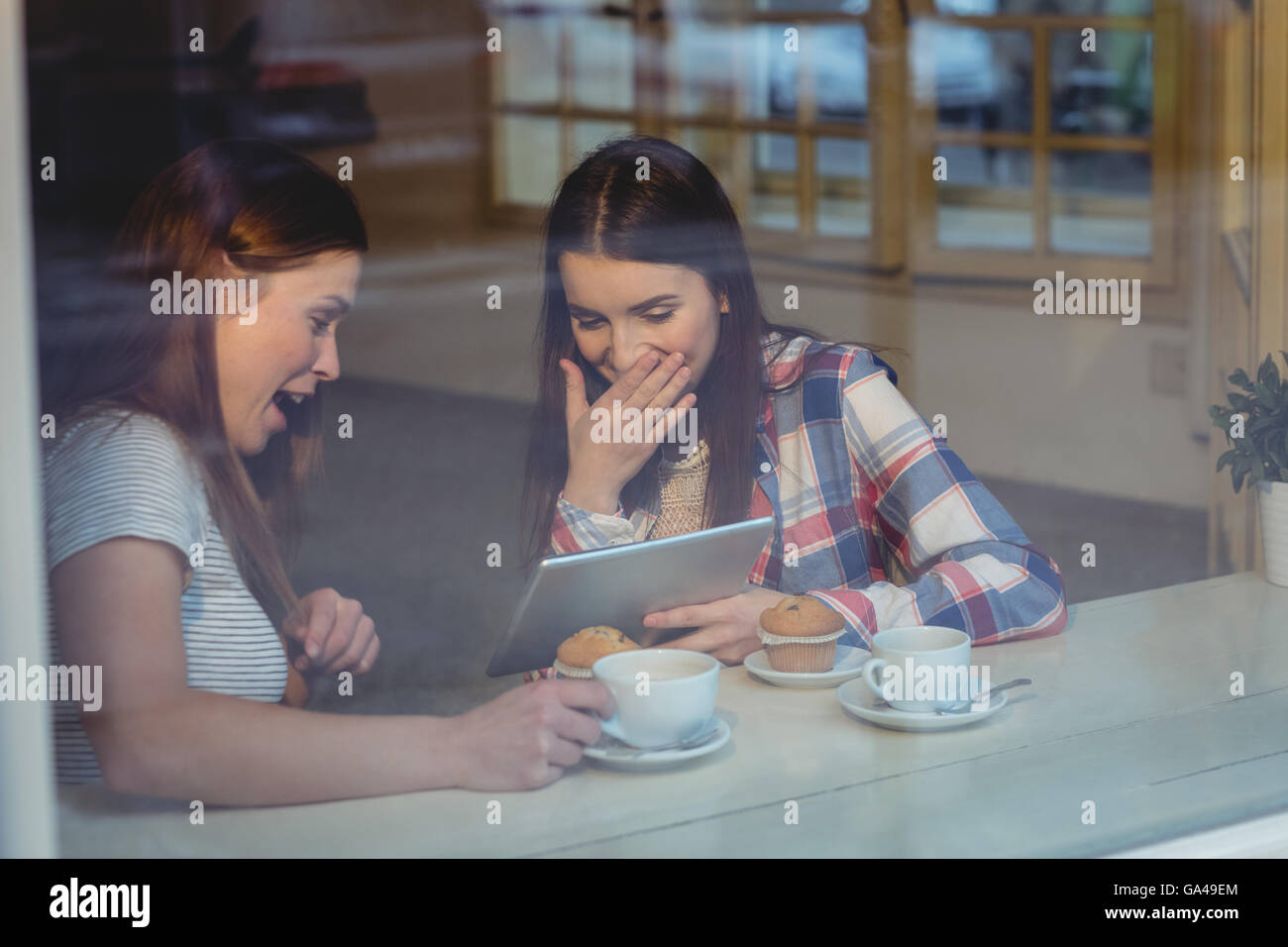 Cheerful women using digital tablet at coffee shop Banque D'Images