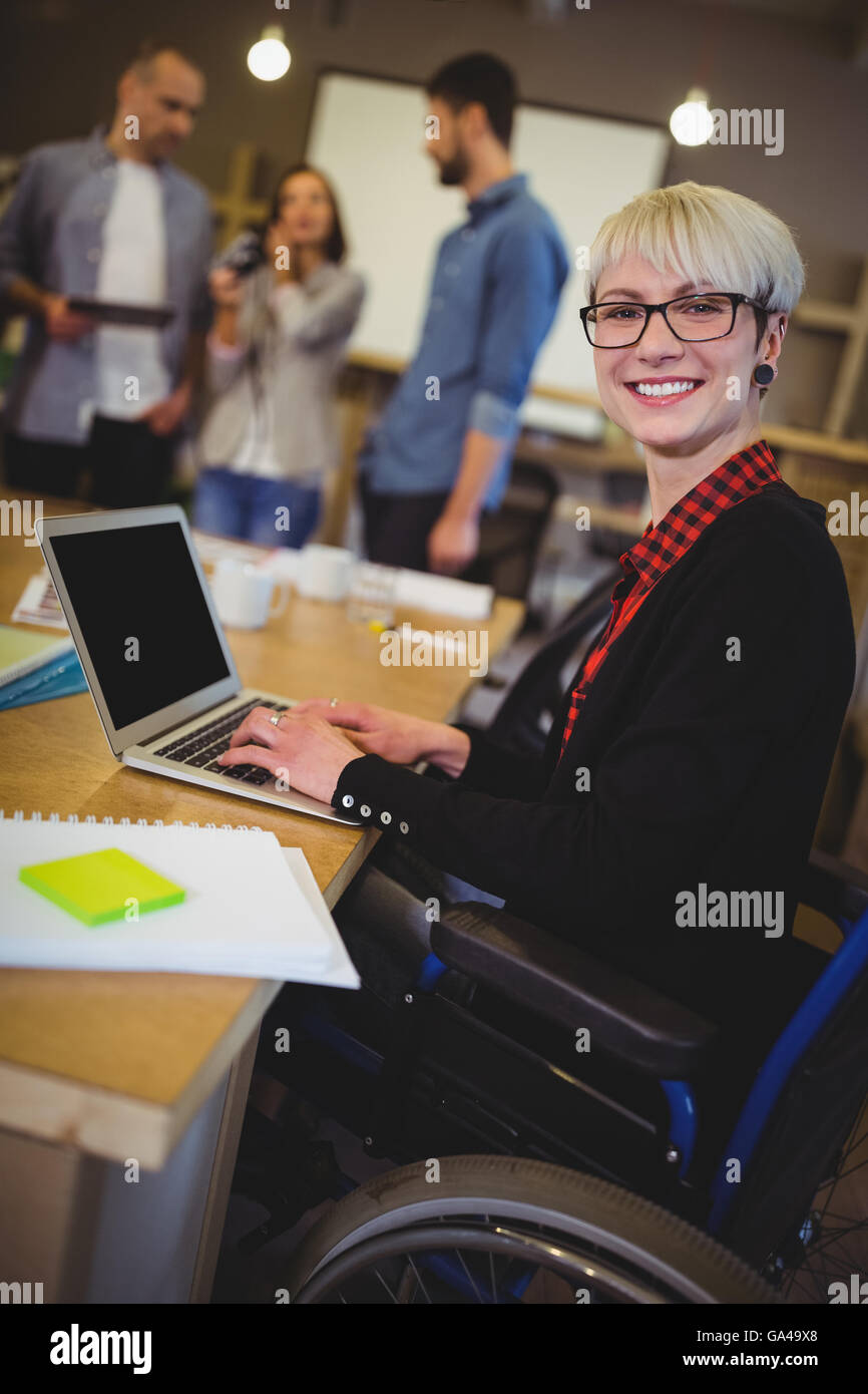 Mobilité Smiling businesswoman using laptop at desk Banque D'Images