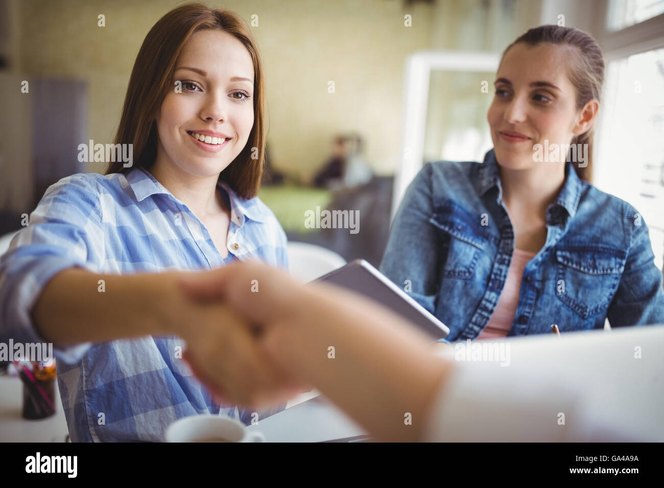 Businesswomen shaking hands in creative office Banque D'Images