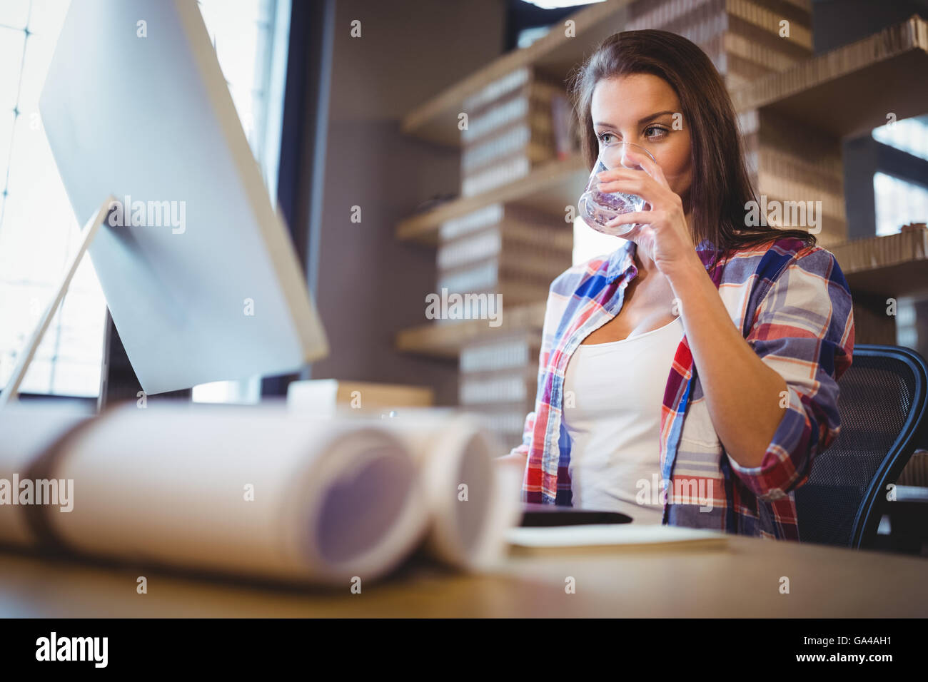 Businesswoman looking at ordinateur pendant que l'eau potable Banque D'Images