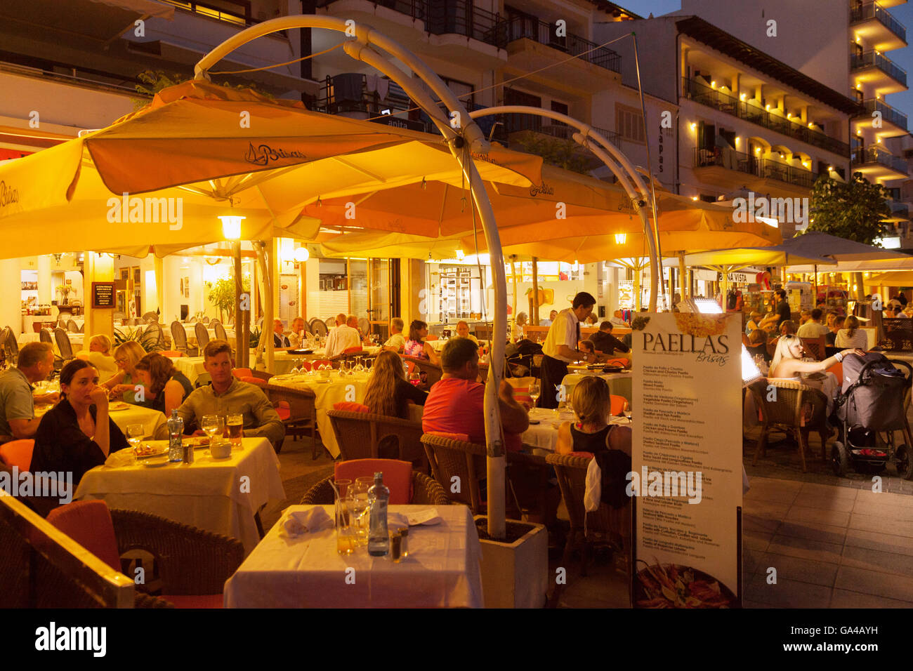 Les gens assis à un restaurant paella paella manger la nuit, Puerto Pollensa, Mallorca, Espagne Europe Banque D'Images