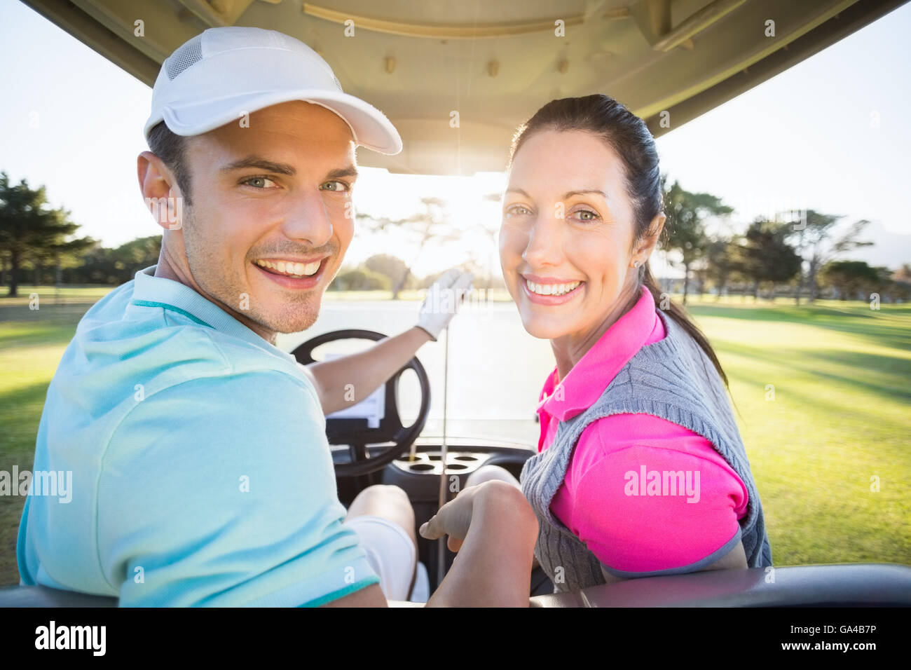 Cheerful couple sitting in golf golfeur bugggy Banque D'Images