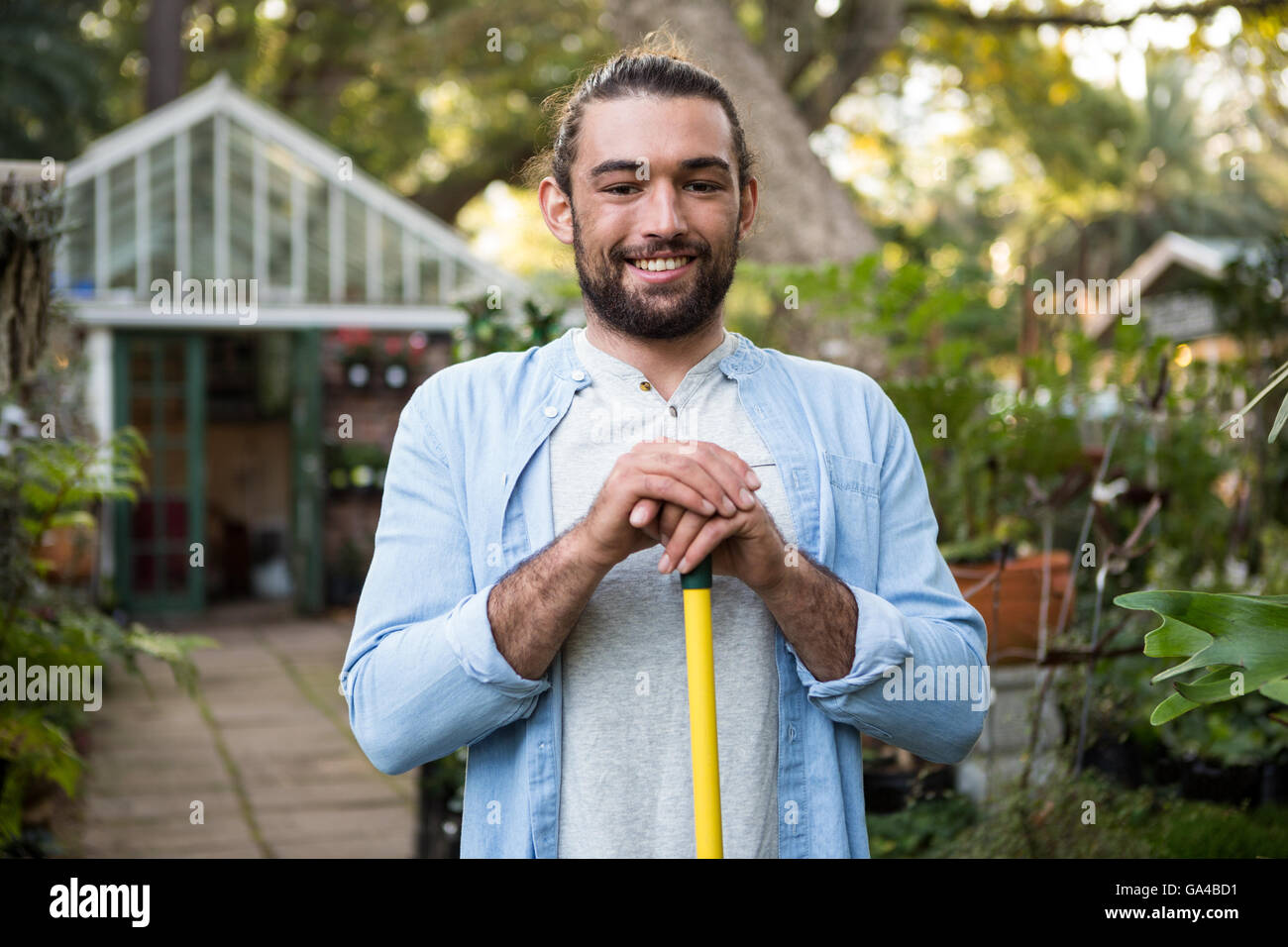 Portrait de jardinier heureux avec l'outil de travail au jardin Banque D'Images
