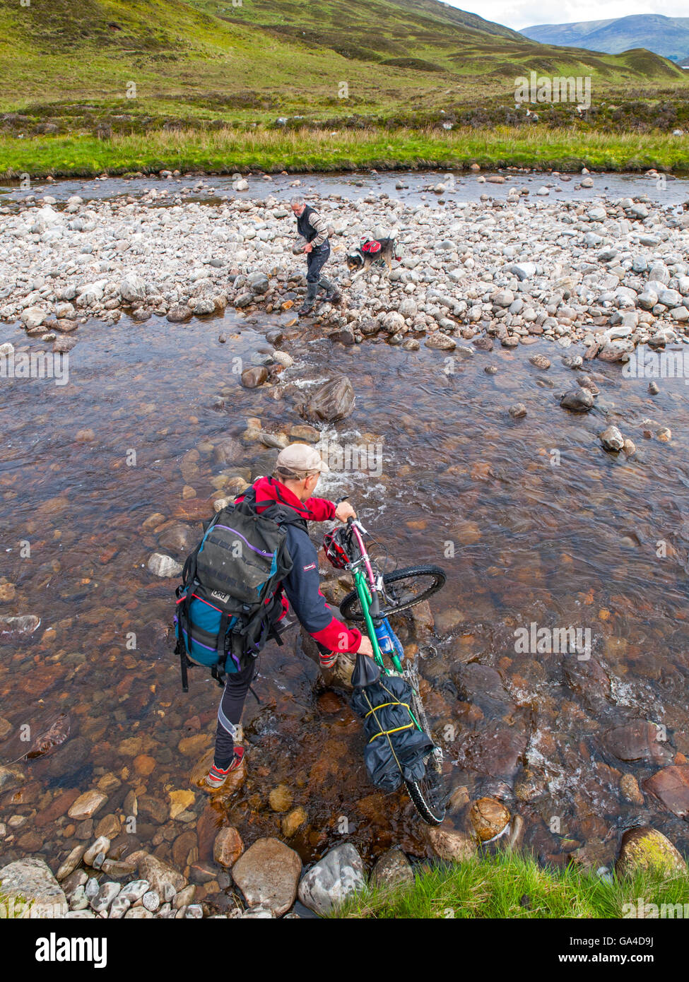 Une rivière à gué cycliste dans les Cairngorms, l'Écosse, tandis que sur un vélo-emballage expedition Banque D'Images
