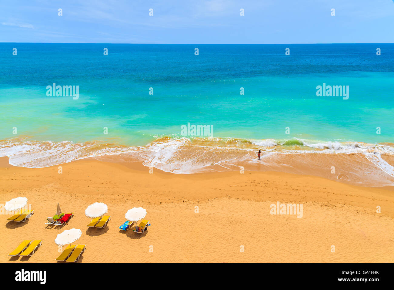 Parasols et jeune femme en mer sur belle plage de Praia da Rocha, Algarve, Portugal Banque D'Images