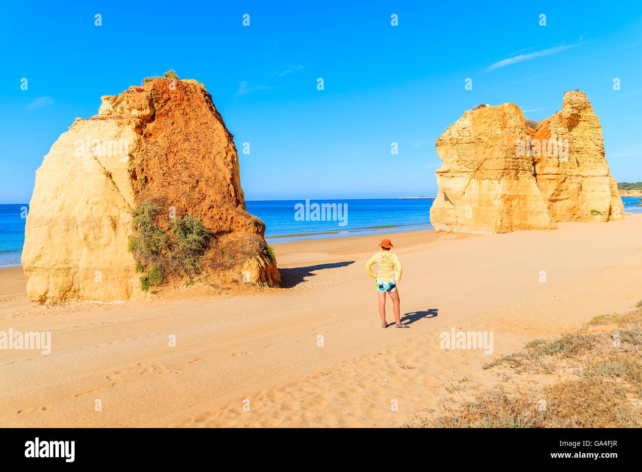 Les roches de couleur d'or et les jeunes'femme debout sur plage de Praia da Rocha, Portugal Banque D'Images