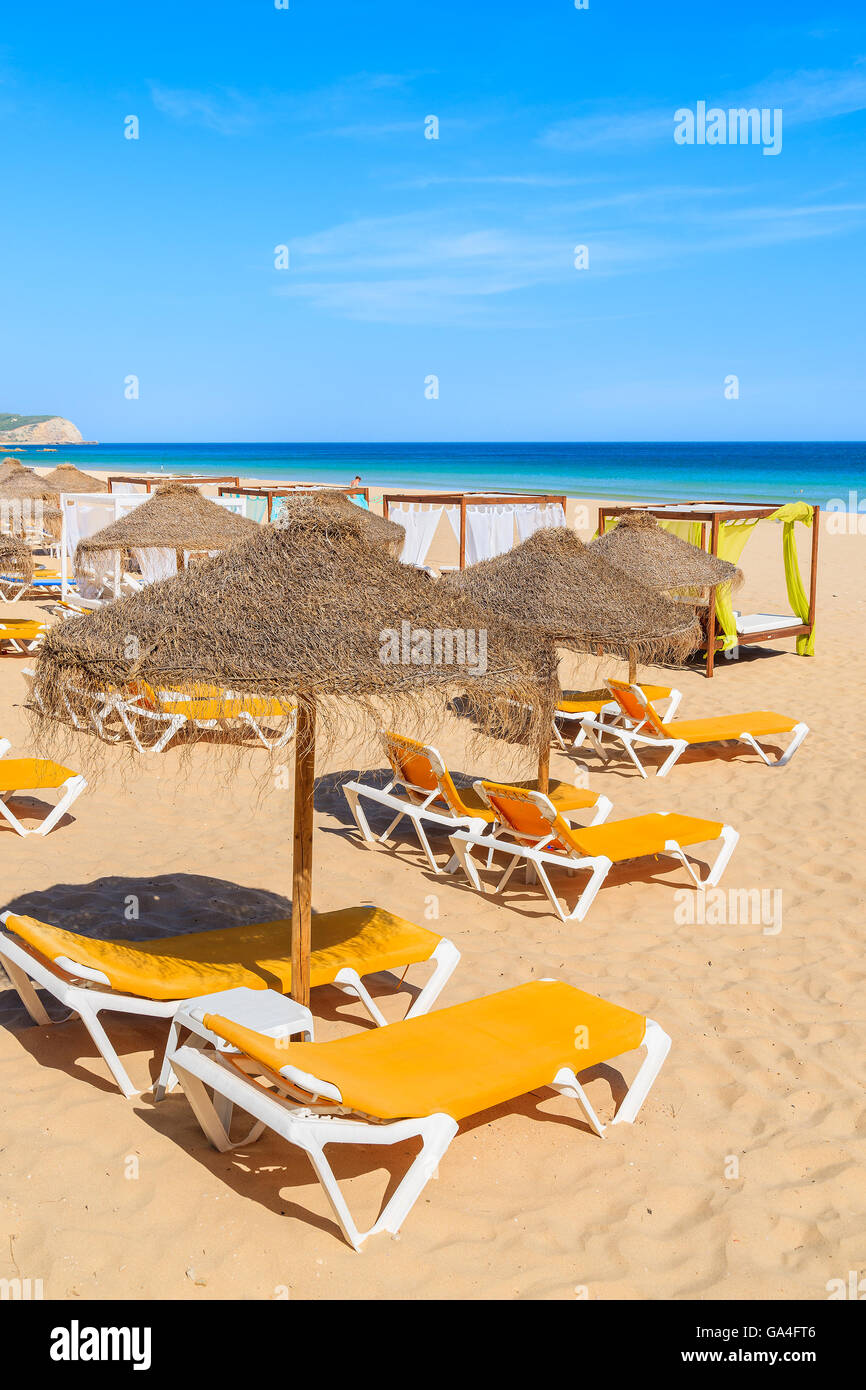 De parasols et de chaises longues sur la plage de sable doré dans Salema ville, Portugal Banque D'Images