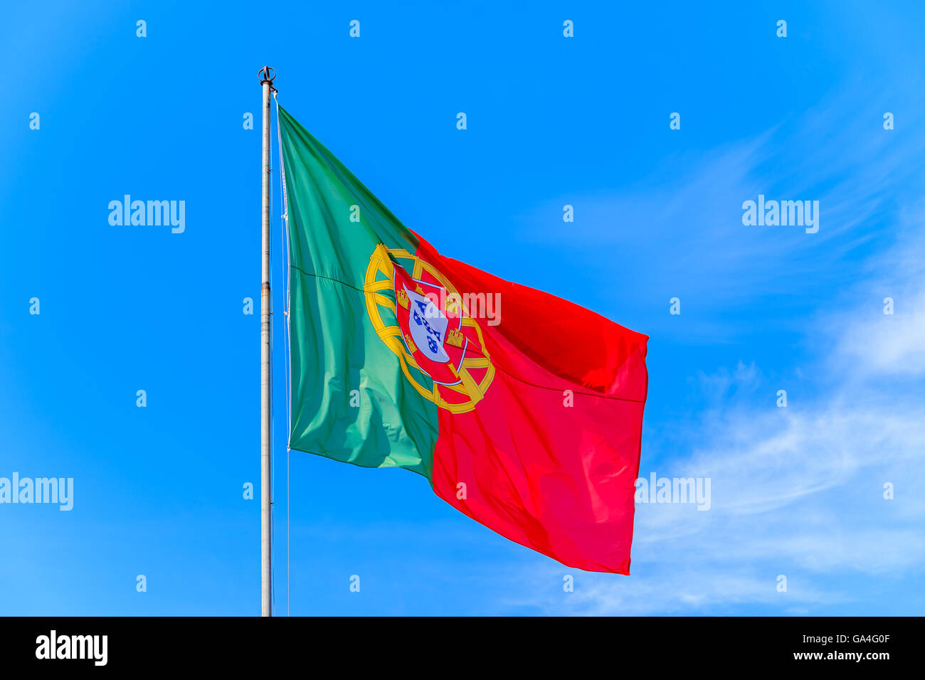 Brandir le drapeau portugais dans le vent contre un fond de ciel bleu au château de Silves, Portugal Banque D'Images