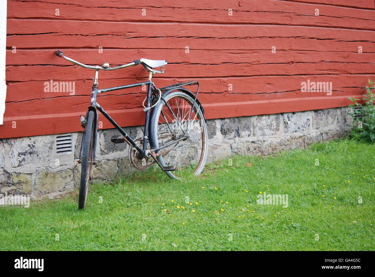 Vieux vélo appuyé contre mur rouge Banque D'Images
