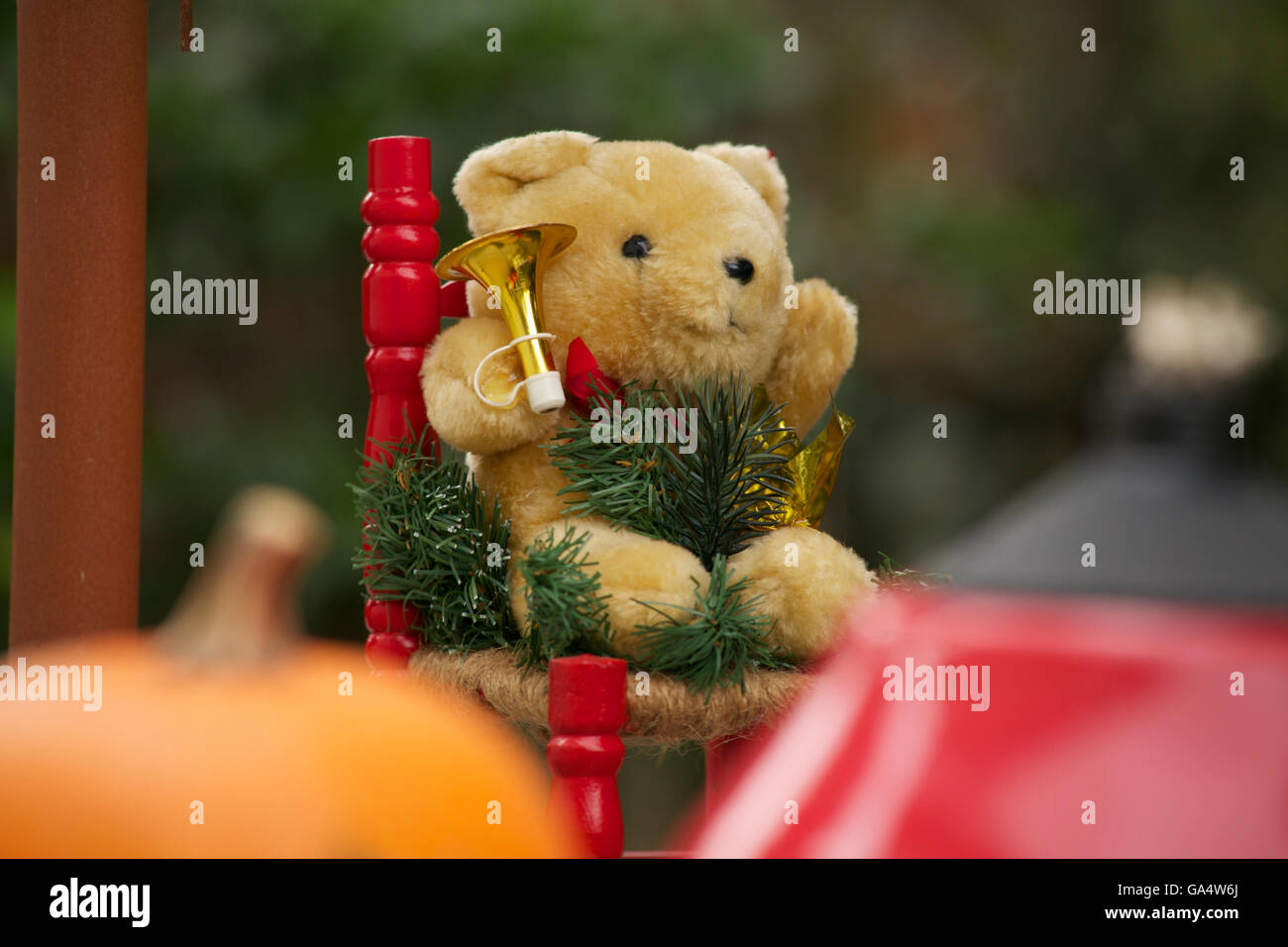 Mignon ours en peluche avec des décorations de Noël assis dans un fauteuil rouge avec une trompette. Banque D'Images