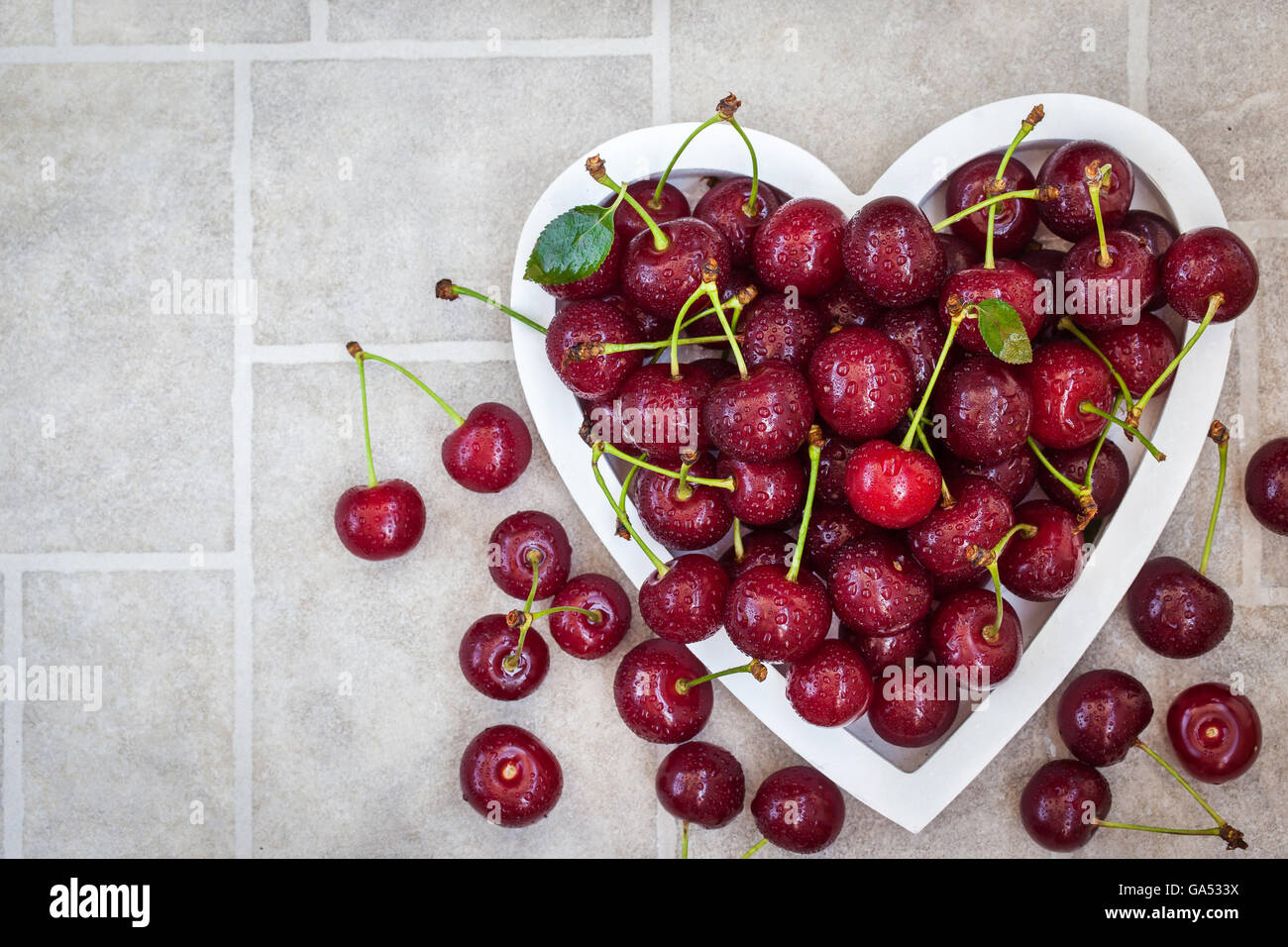 L'été humide frais cerise dans bol en forme de coeur Banque D'Images