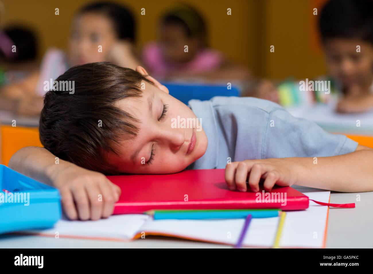 Cute boy sleeping on desk Banque D'Images