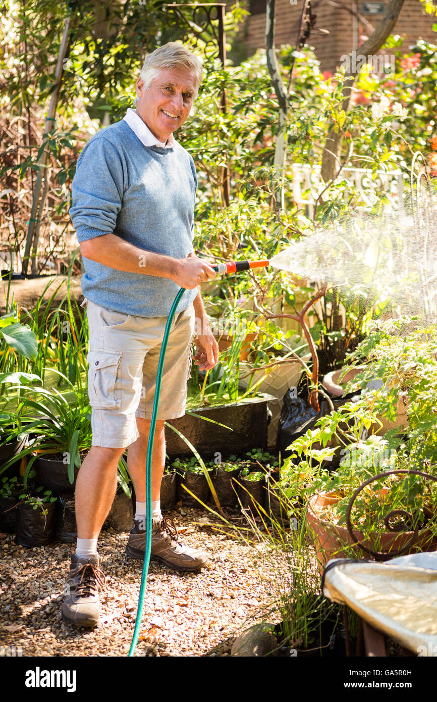 Portrait de jardinier l'arrosage des plantes de jardin à flexible Banque D'Images