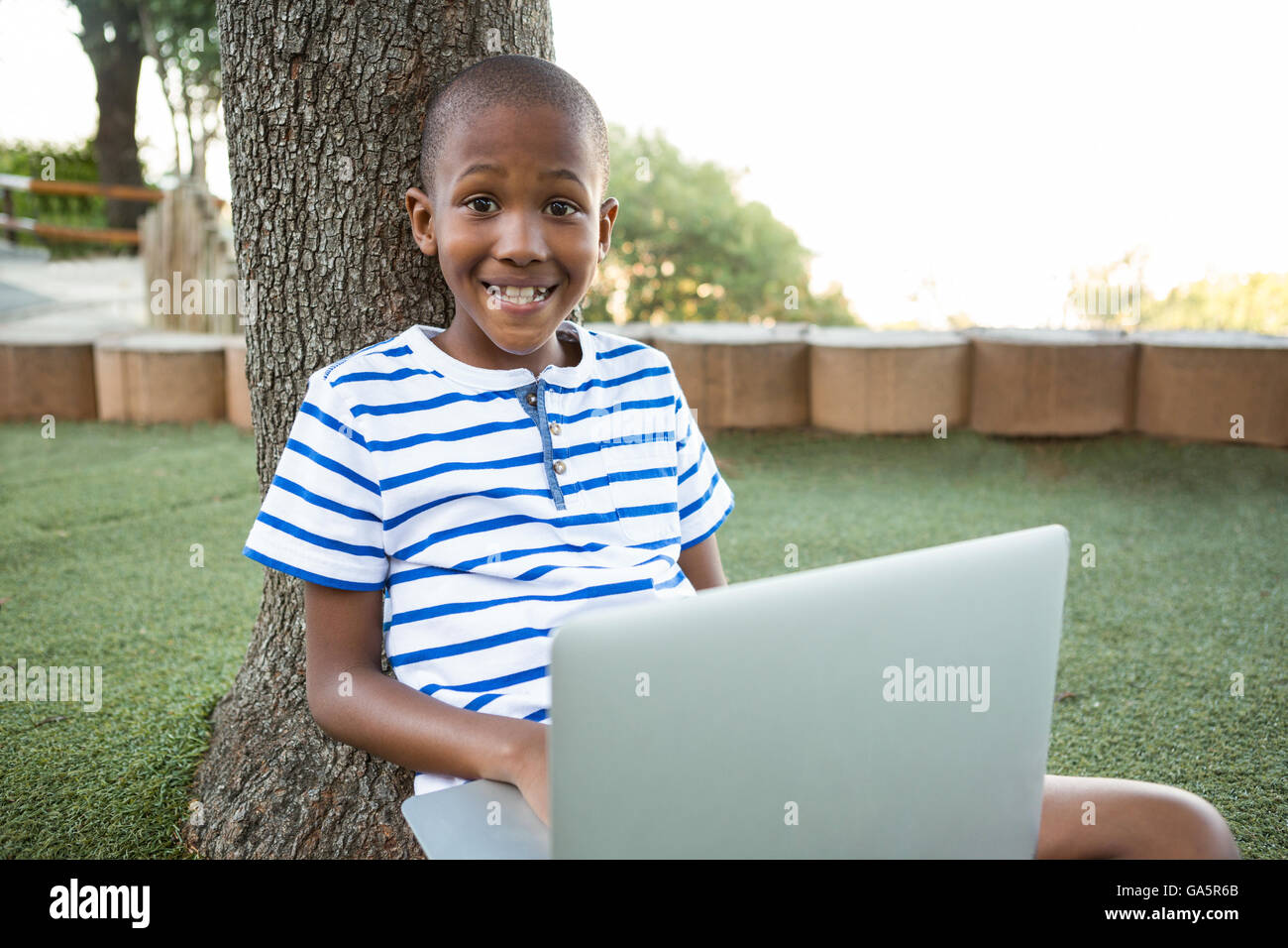 Happy boy using laptop at park Banque D'Images
