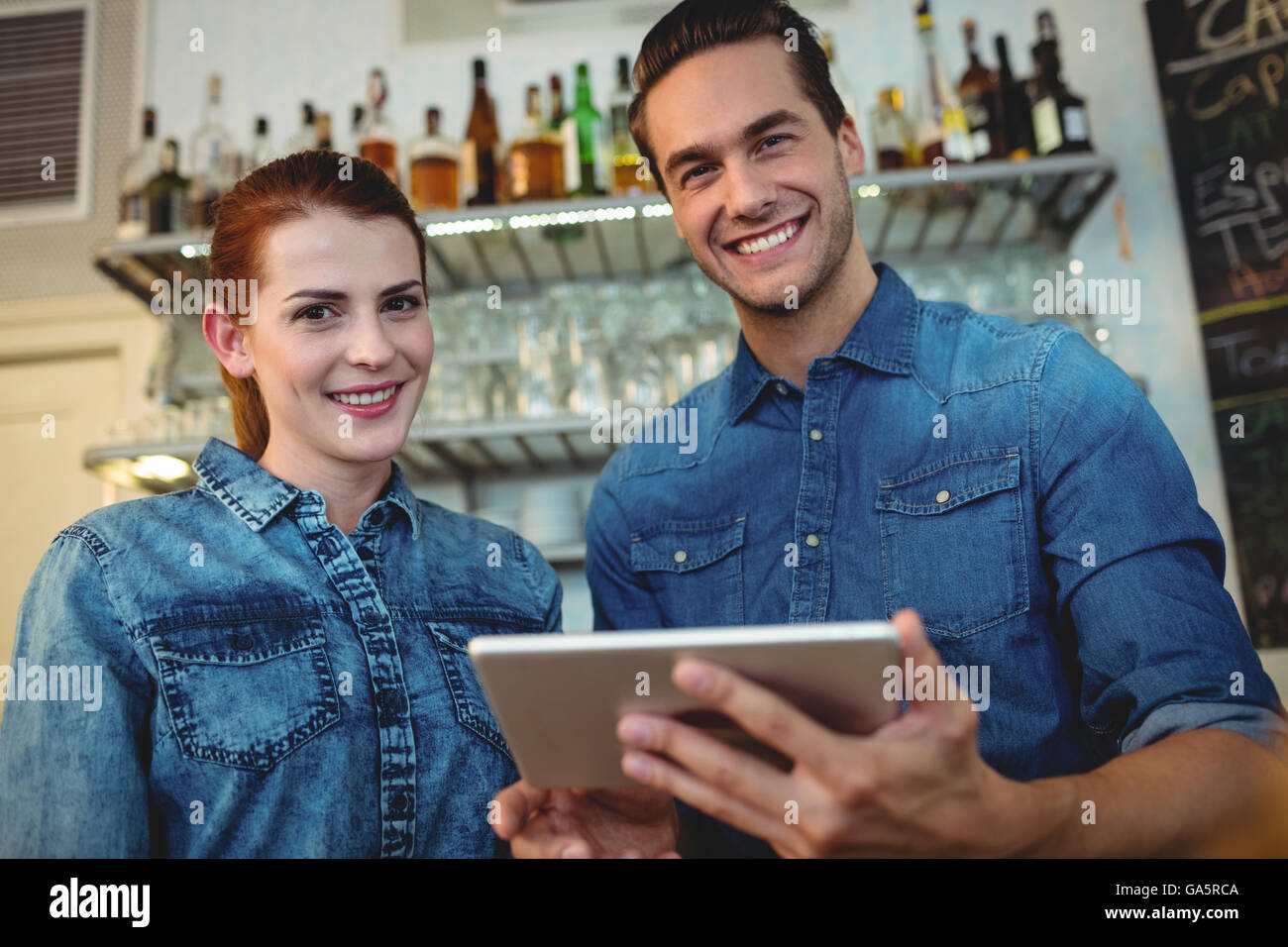 Portrait of cheerful baristas with digital tablet at cafe Banque D'Images