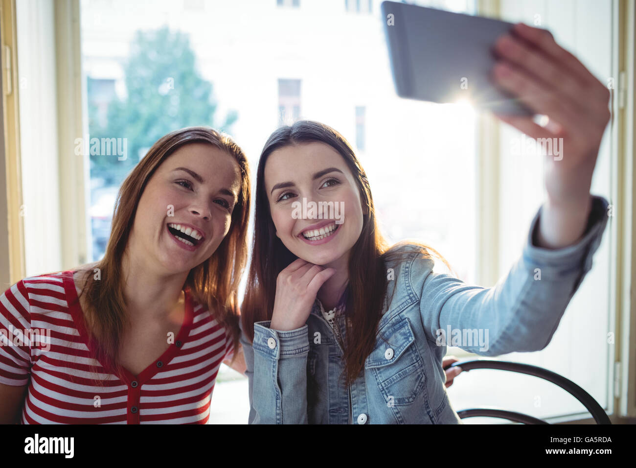 Cheerful female friends prenant du coffee shop selfies Banque D'Images