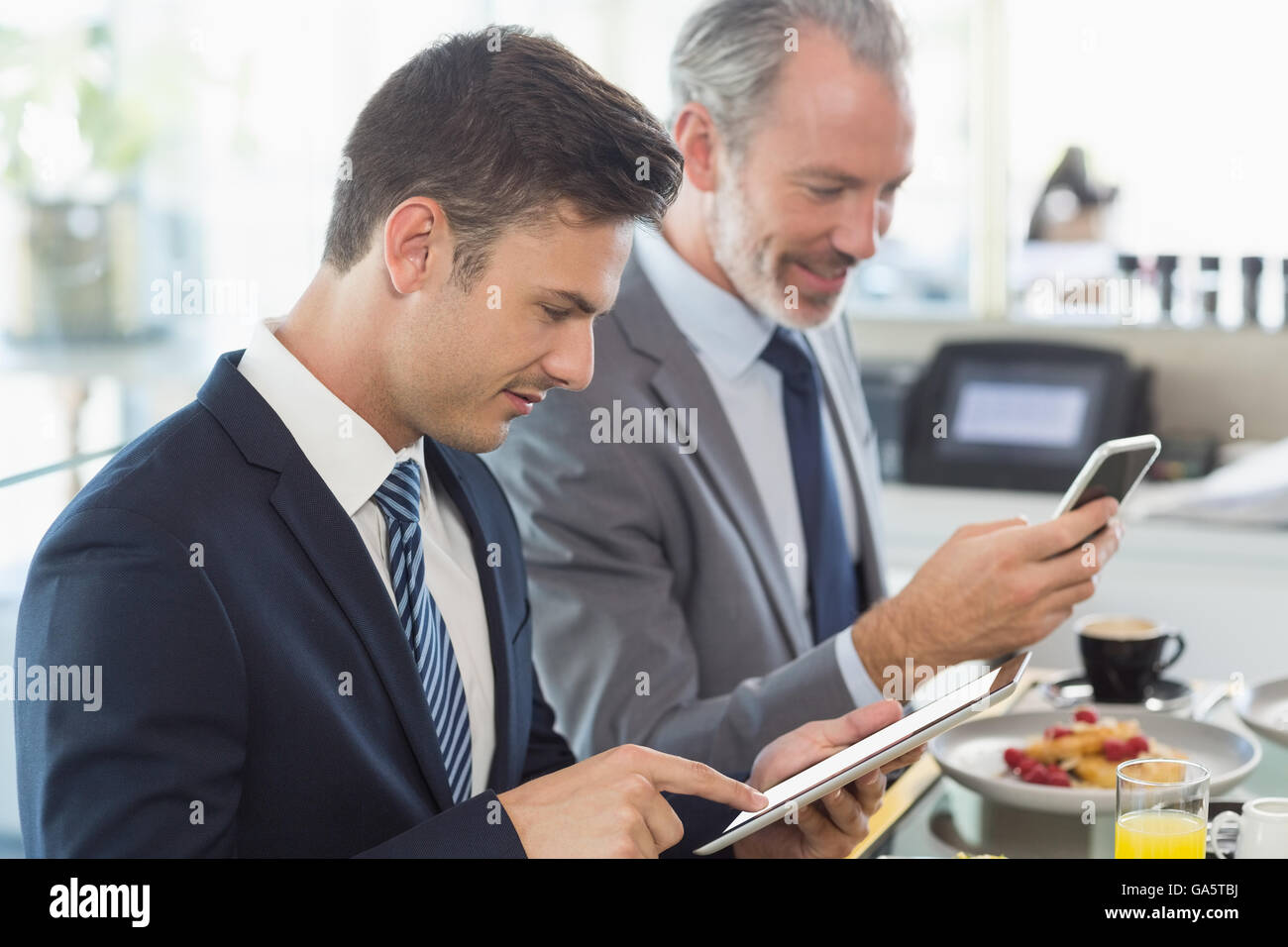 Deux hommes d'affaires à l'aide de téléphone mobile et tablette numérique Banque D'Images