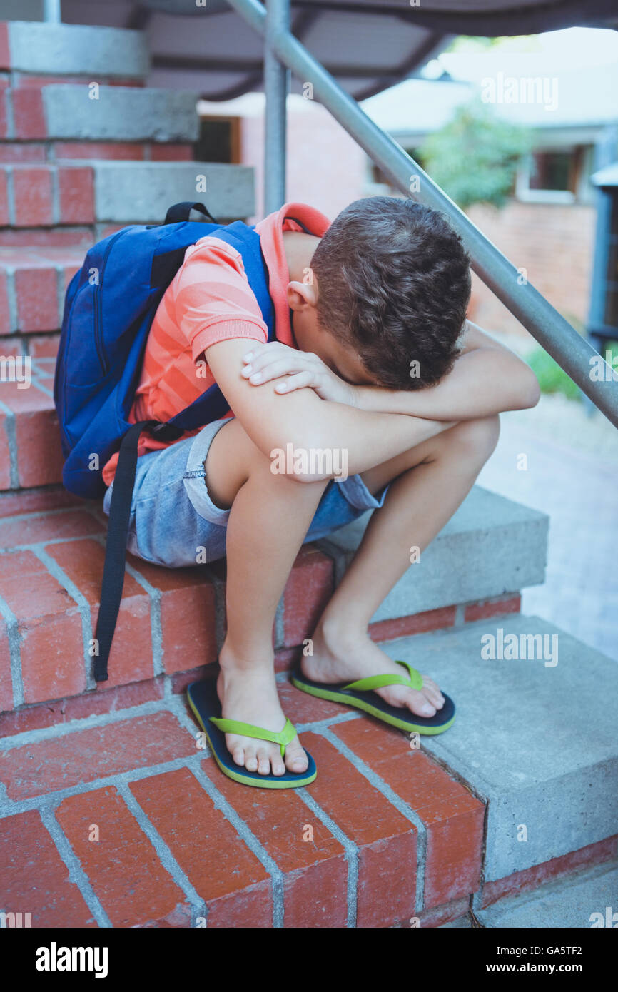 Écolier triste siégeant seul on staircase Banque D'Images