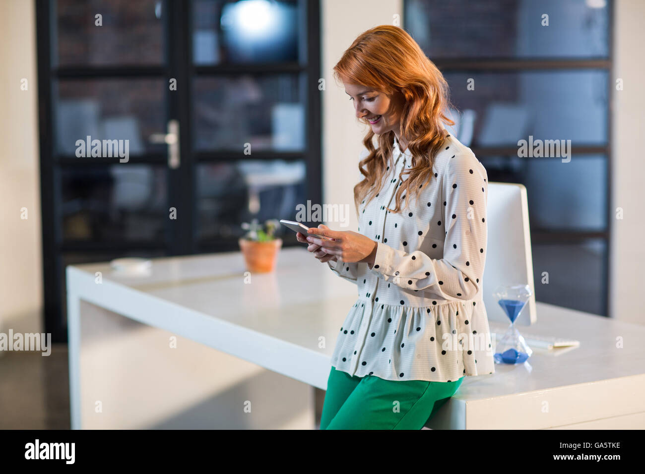 Woman using mobile phone in office Banque D'Images