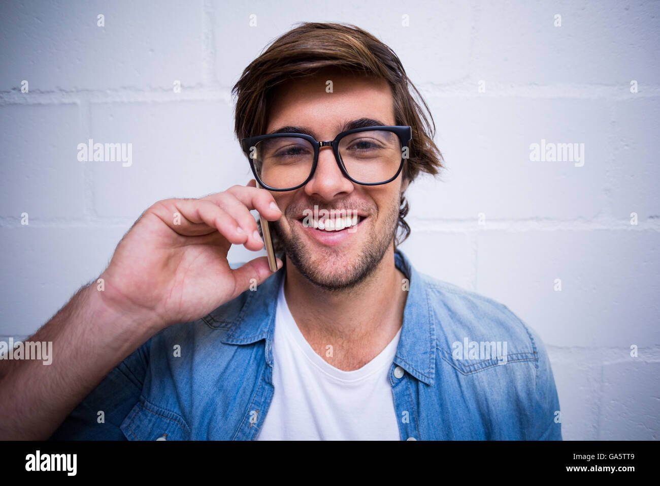 Portrait d'un homme parlant au téléphone contre le mur Banque D'Images