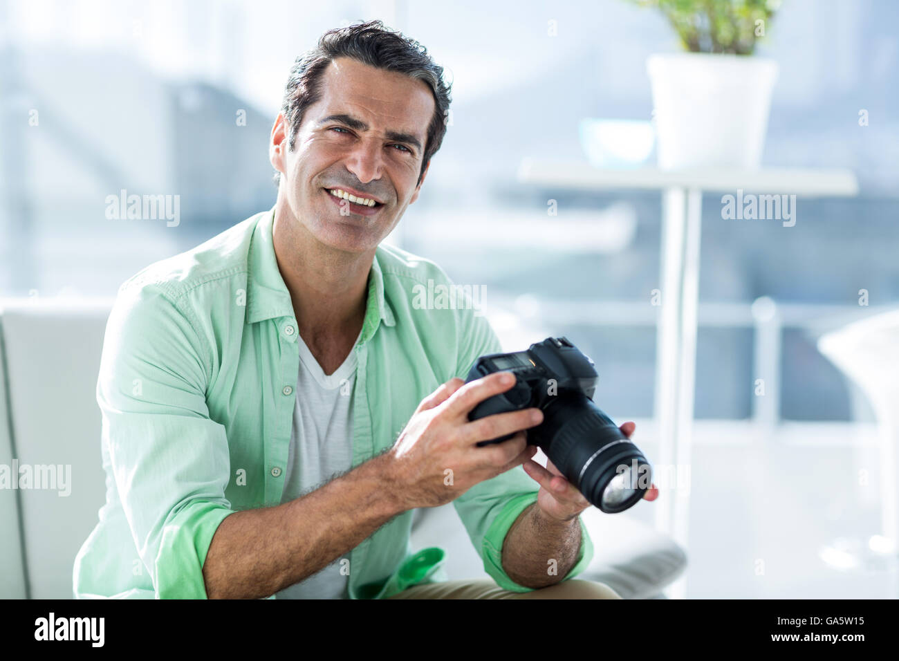 Mid adult man holding camera at home Banque D'Images
