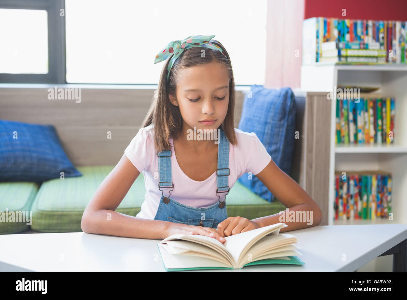 School girl reading a book in library Banque D'Images