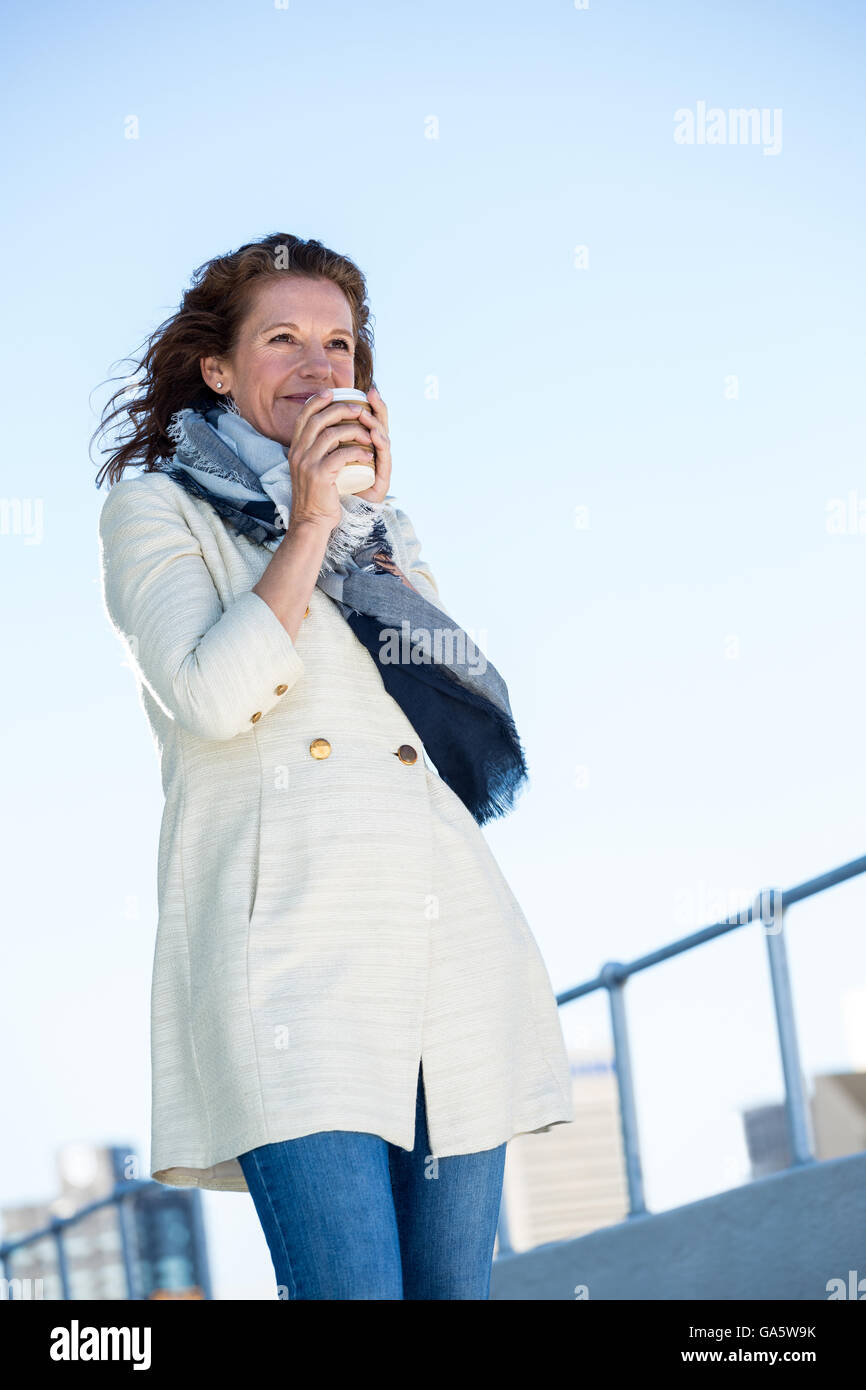 Femme buvant du café contre ciel clair Banque D'Images