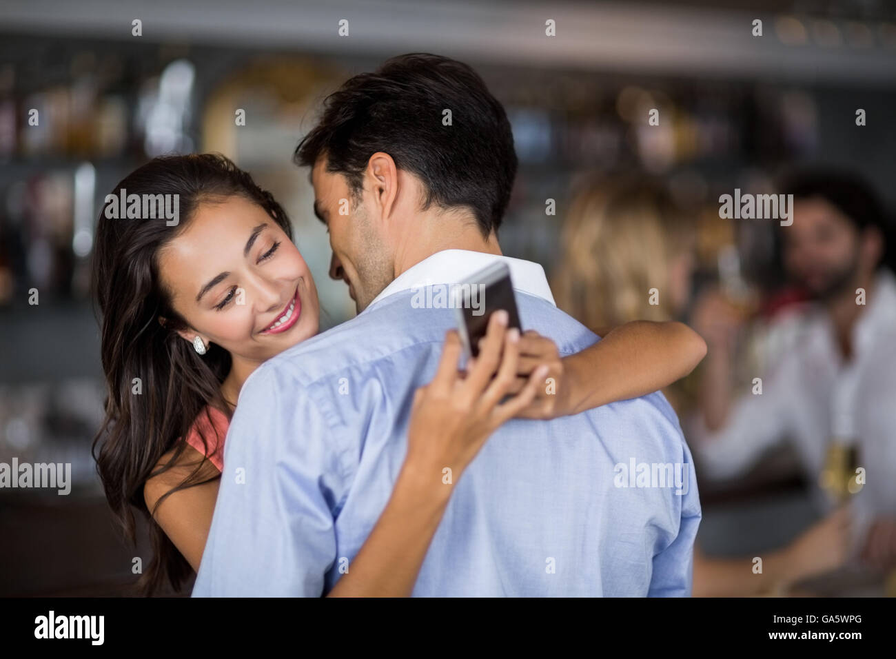 Woman téléphone mobile tout en embrassant l'homme Banque D'Images